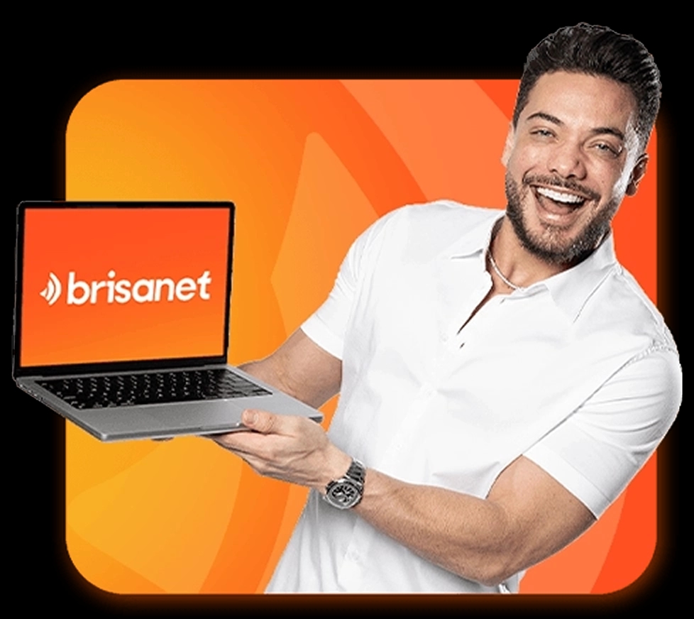 O cantor Wesley Safadão sorrindo com um notebook apoiado nas duas mãos, vestindo uma camisa branca.